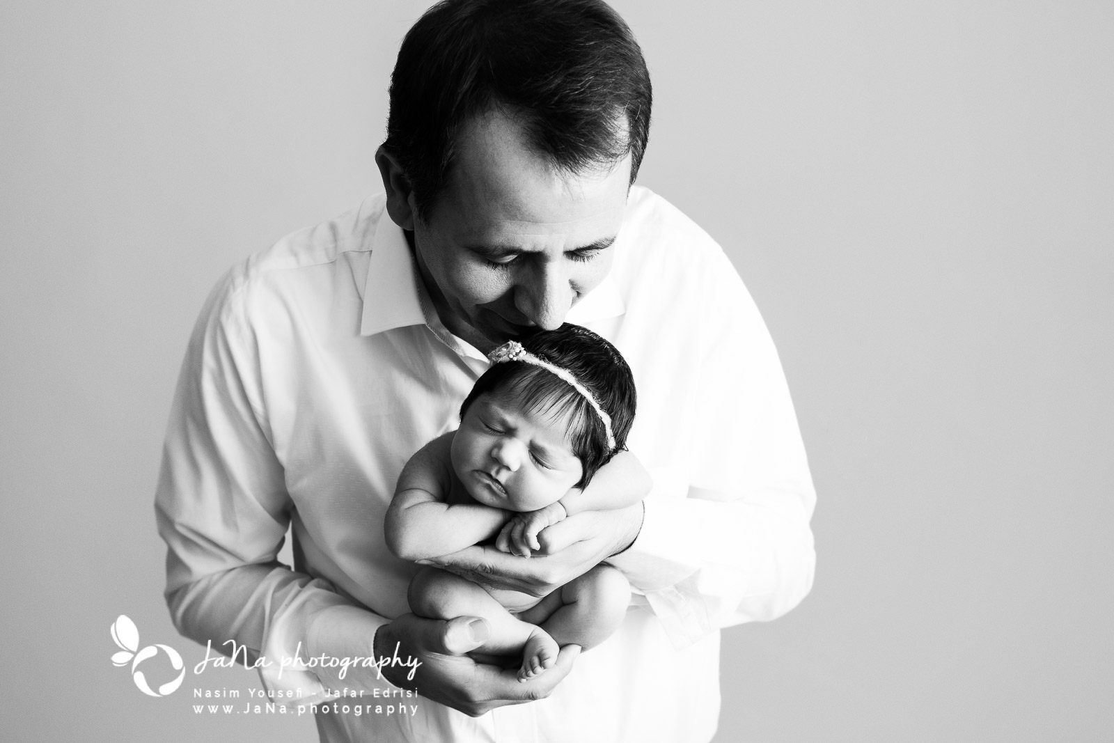 black and white picture of dad holding newborn baby girl in his hand