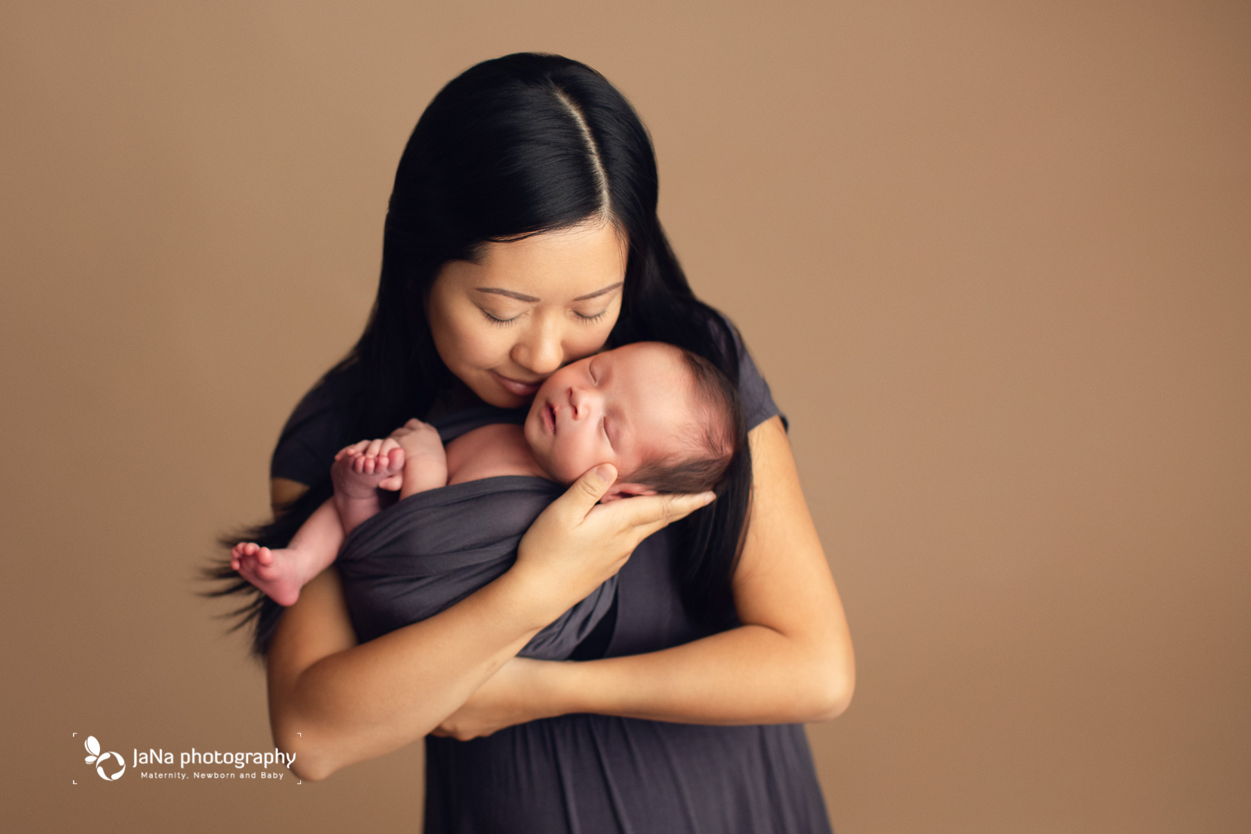mommy is holding her newborn - mocha color background 