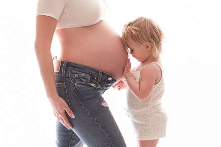 baby girl kissing mommy's maternity belly 