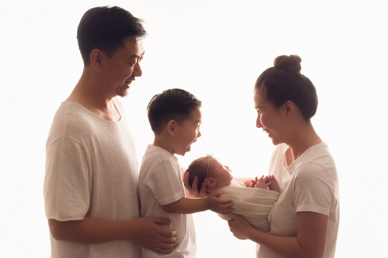 newborn family photography with siblings smile in white background