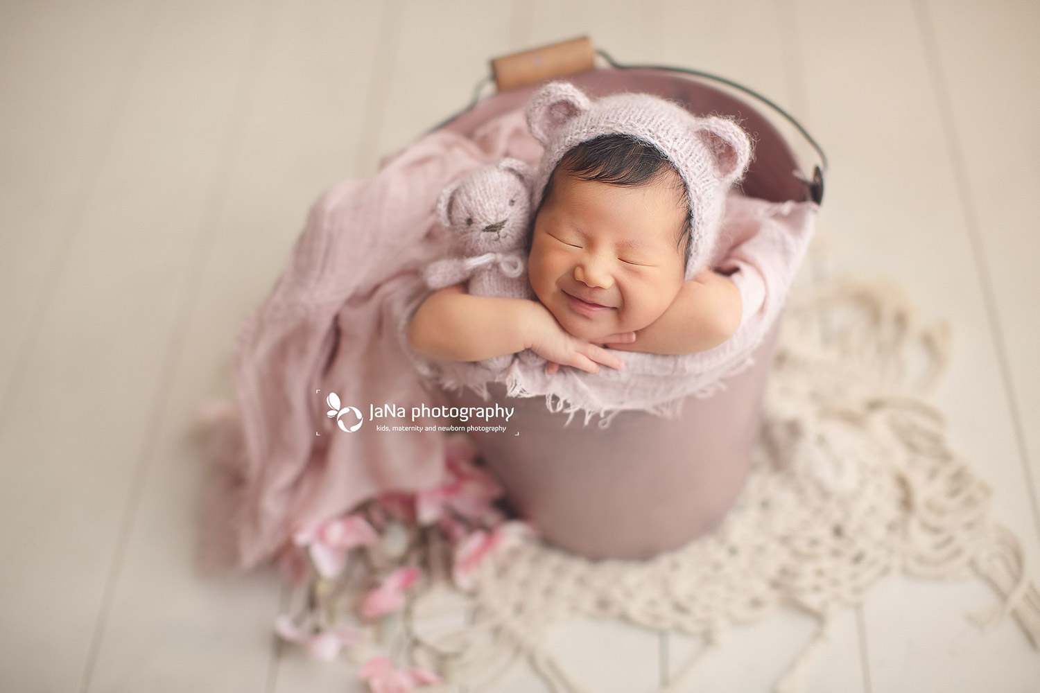 newborn baby girl in a pink bucket smiling | jana photography