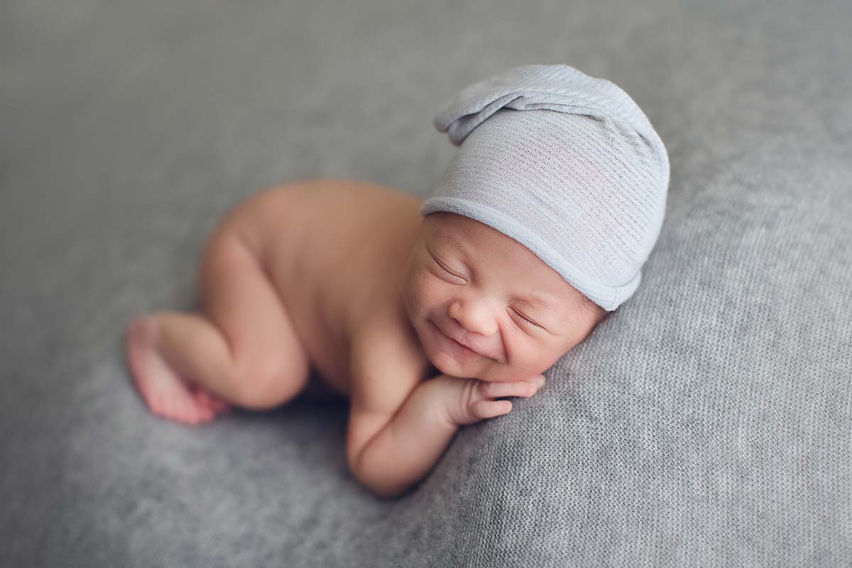 newborn baby boy photography - grey background - hat and smile 