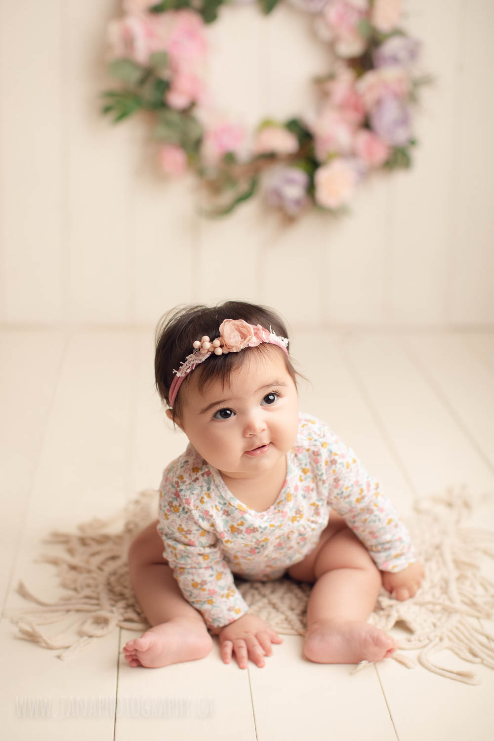 Baby girl sitting with headband and floral pink dress