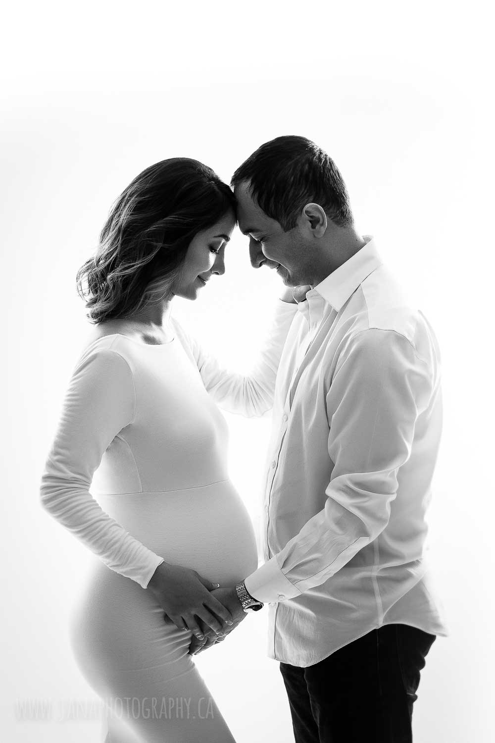 Mom and dad maternity photo in front of each other in black and white