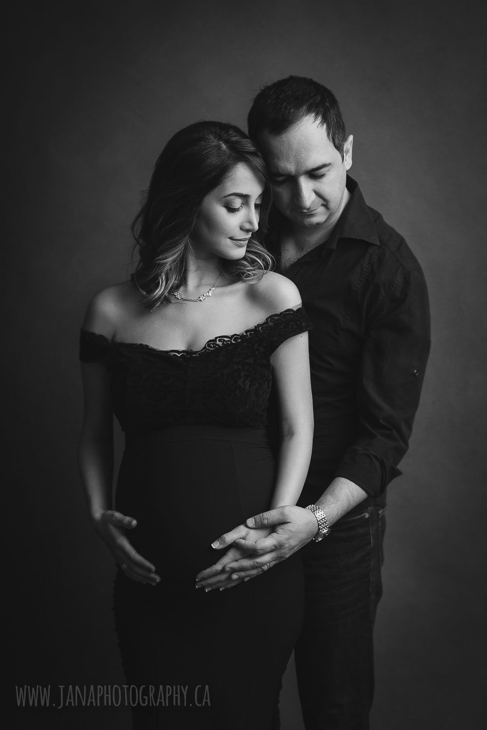 Black and white maternity photography mom standing in front of dad looking down