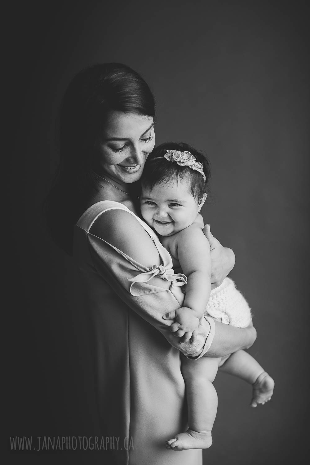 Mom is holding baby girl smiling in a black and white picture