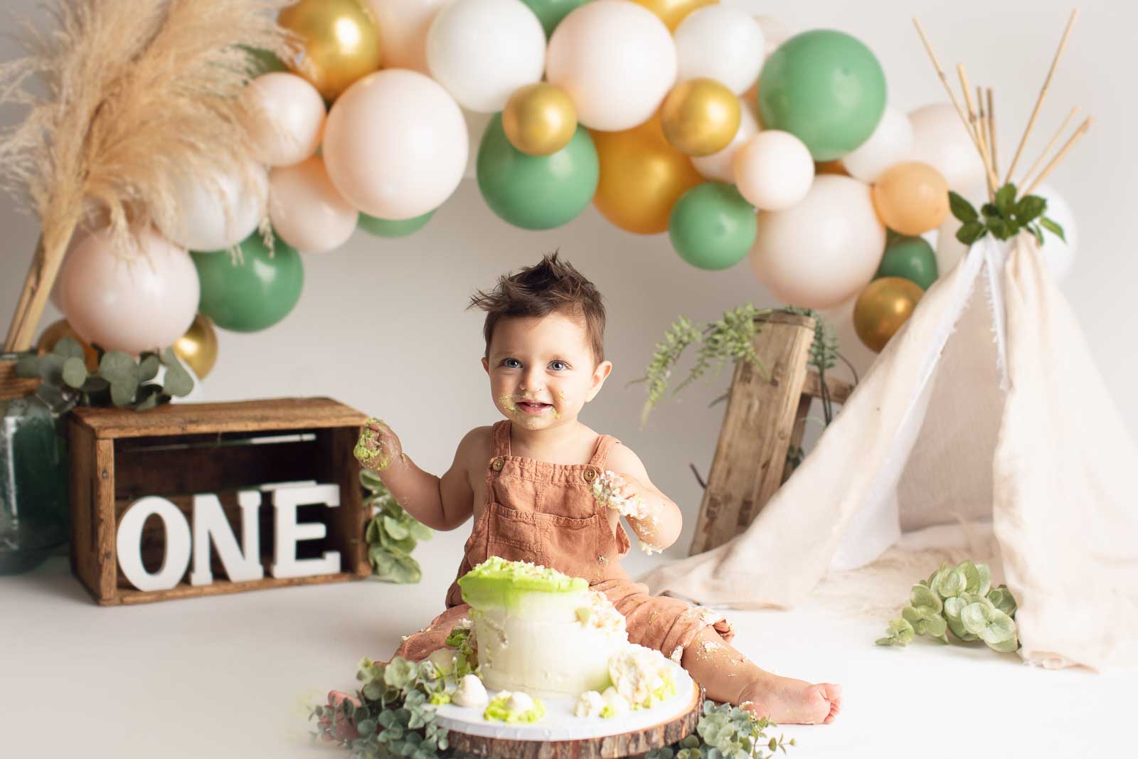 blond boy smashing cake in pastel green colour background