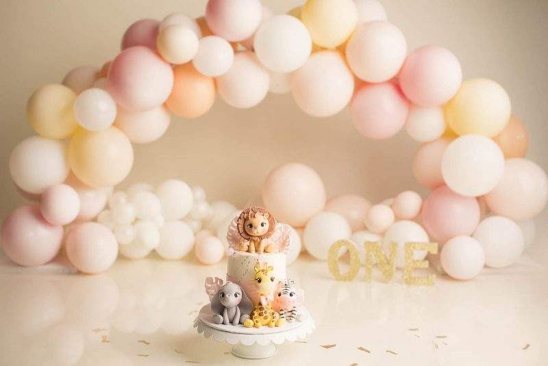 pink white pastel colour balloons cake smash setup with safari cake for girls