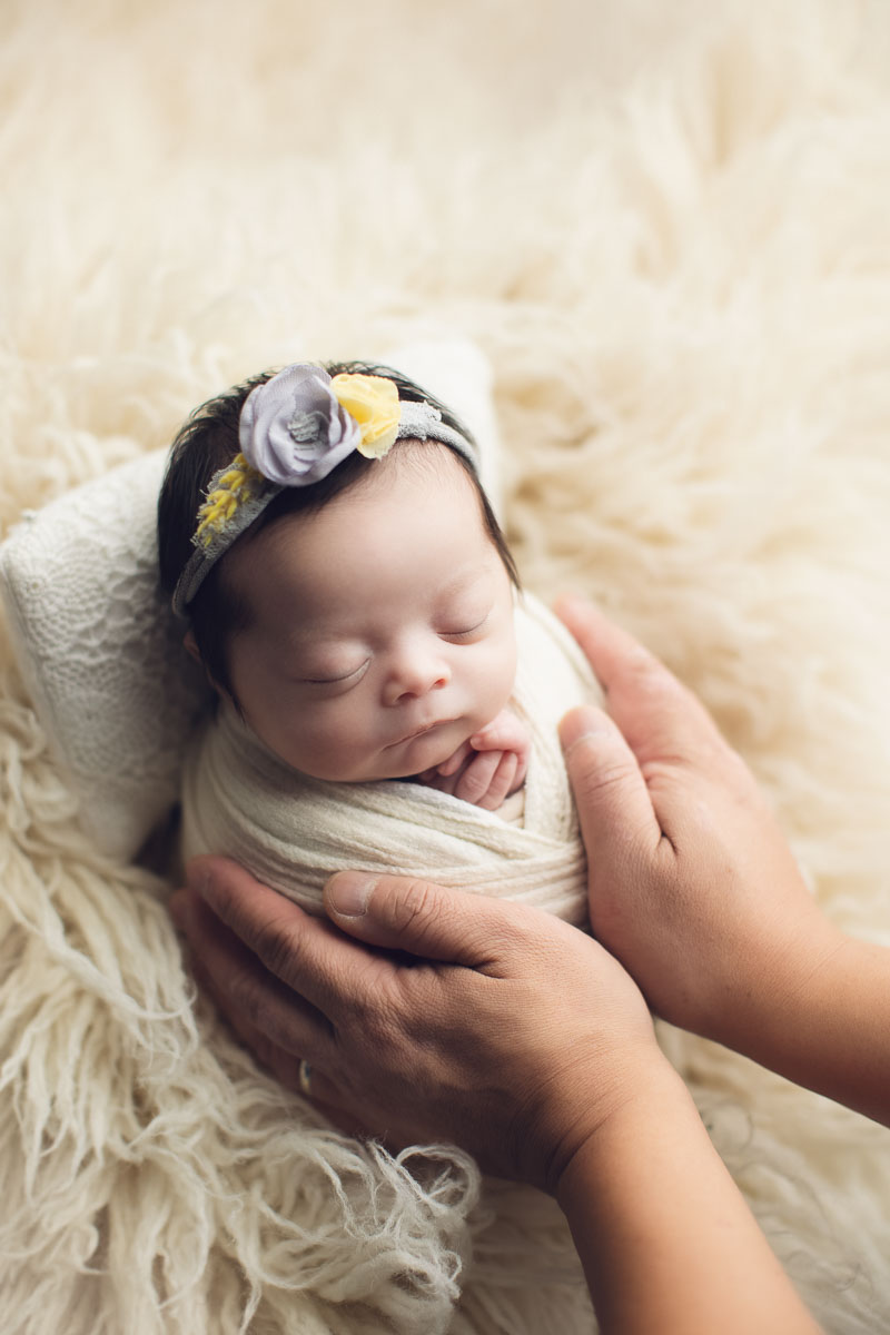 newborn photography girl in light white background and dad hands