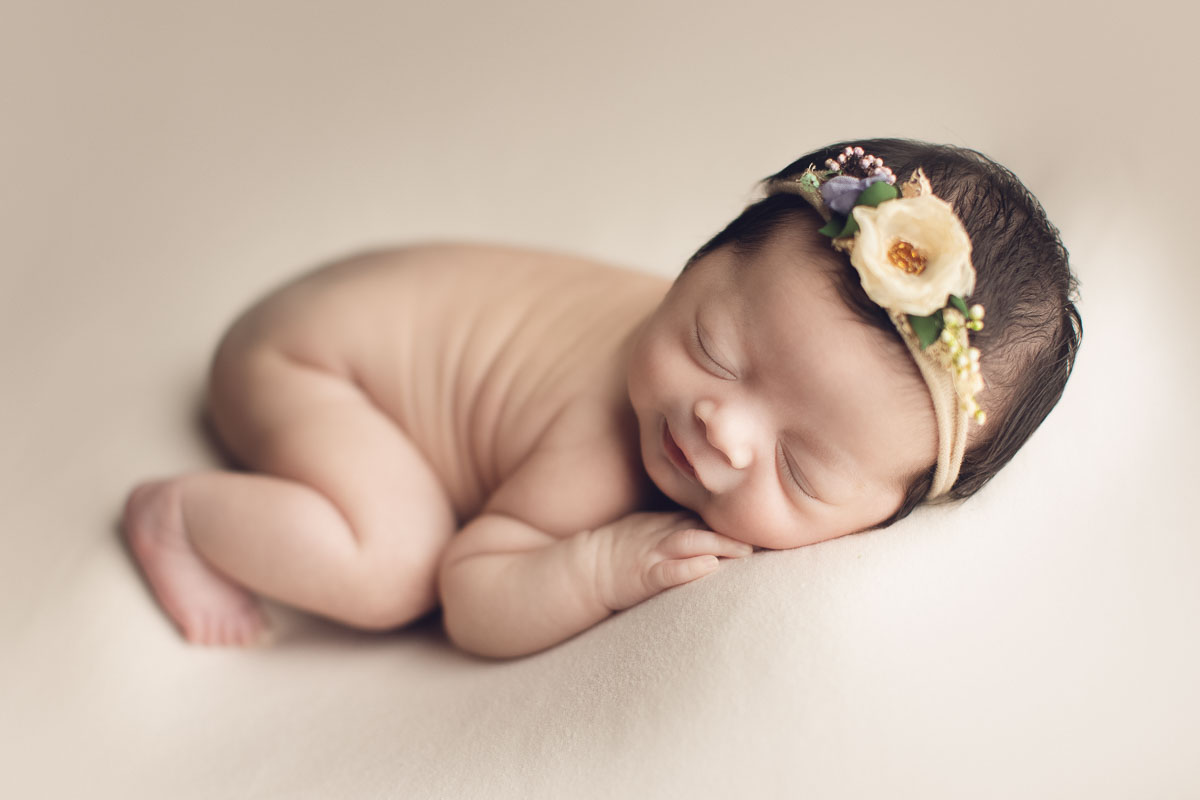 newborn baby girl creamy background smile