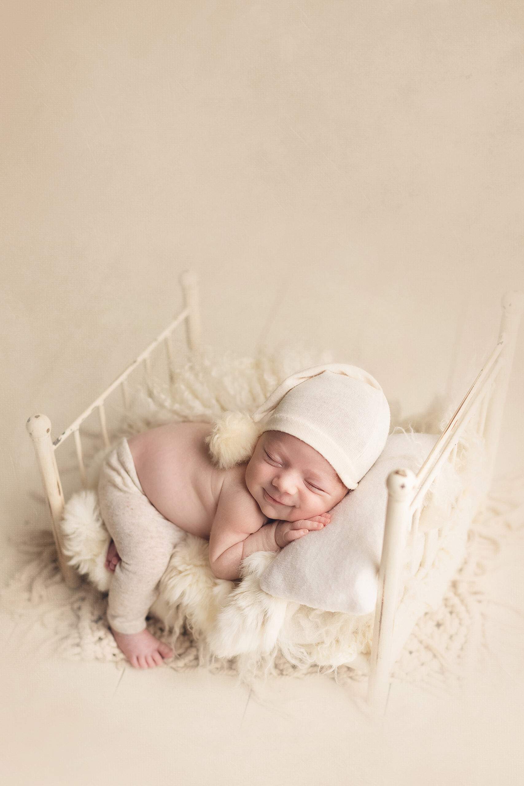  baby boy sleeping in a white bed and smiling