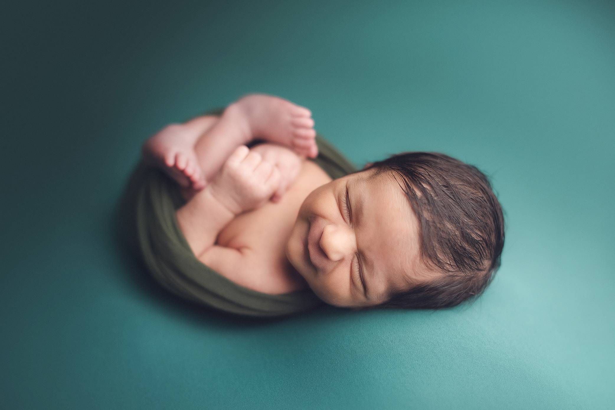 newborn baby boy in a green background smiling