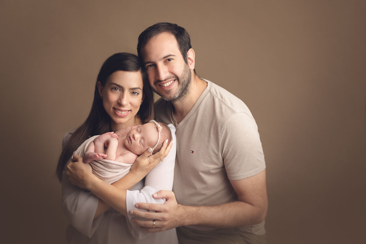 Vancouver - Burnaby and surrey - newborn photography - mom and dad holding baby girl on a studio light brown background