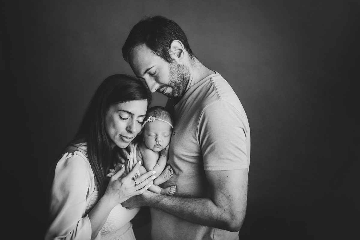 Vancouver - Burnaby and surrey - newborn photography - mom and dad holding baby girl on a studio light black background -bw