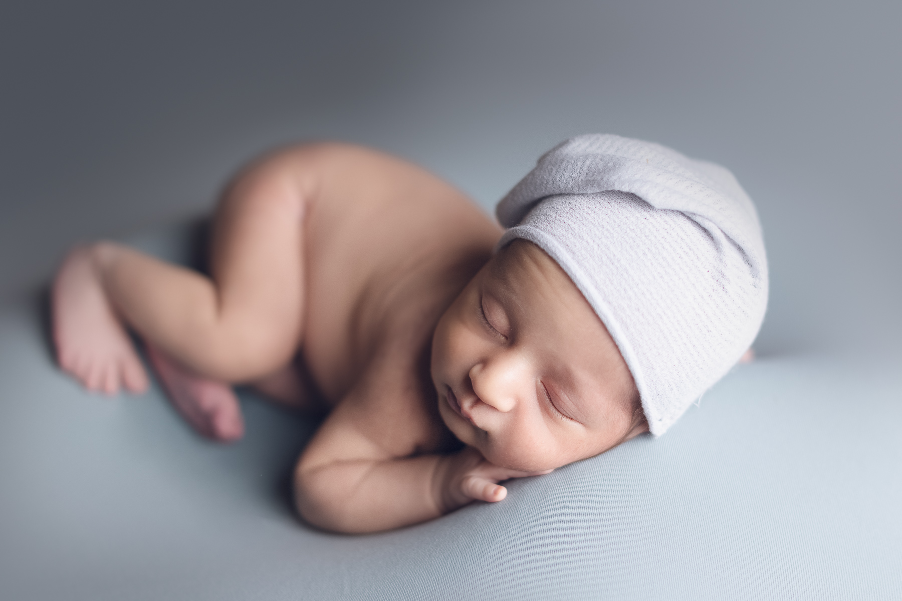 newborn photographer in Vancouver- baby boy on a grey background fabric and hat