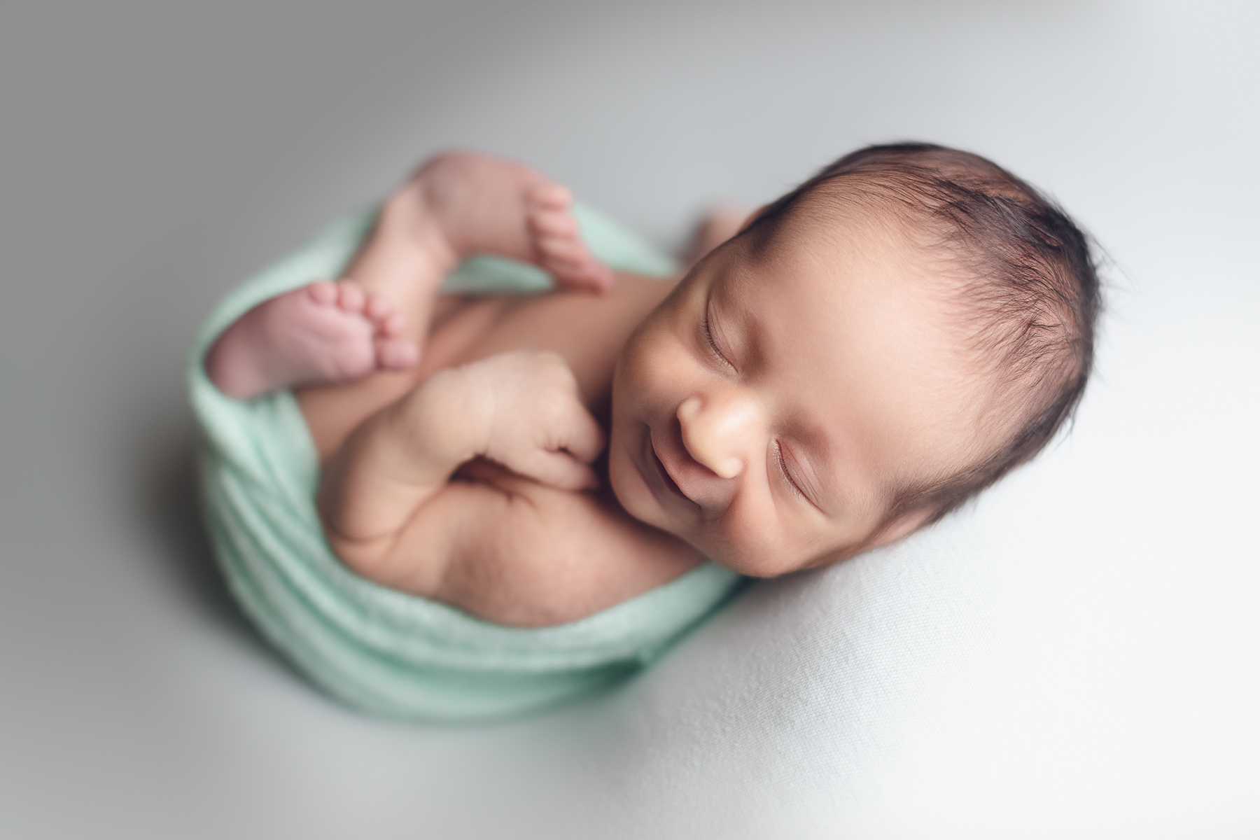 Newborn baby only photography package on sale - baby boy smiling on a green background