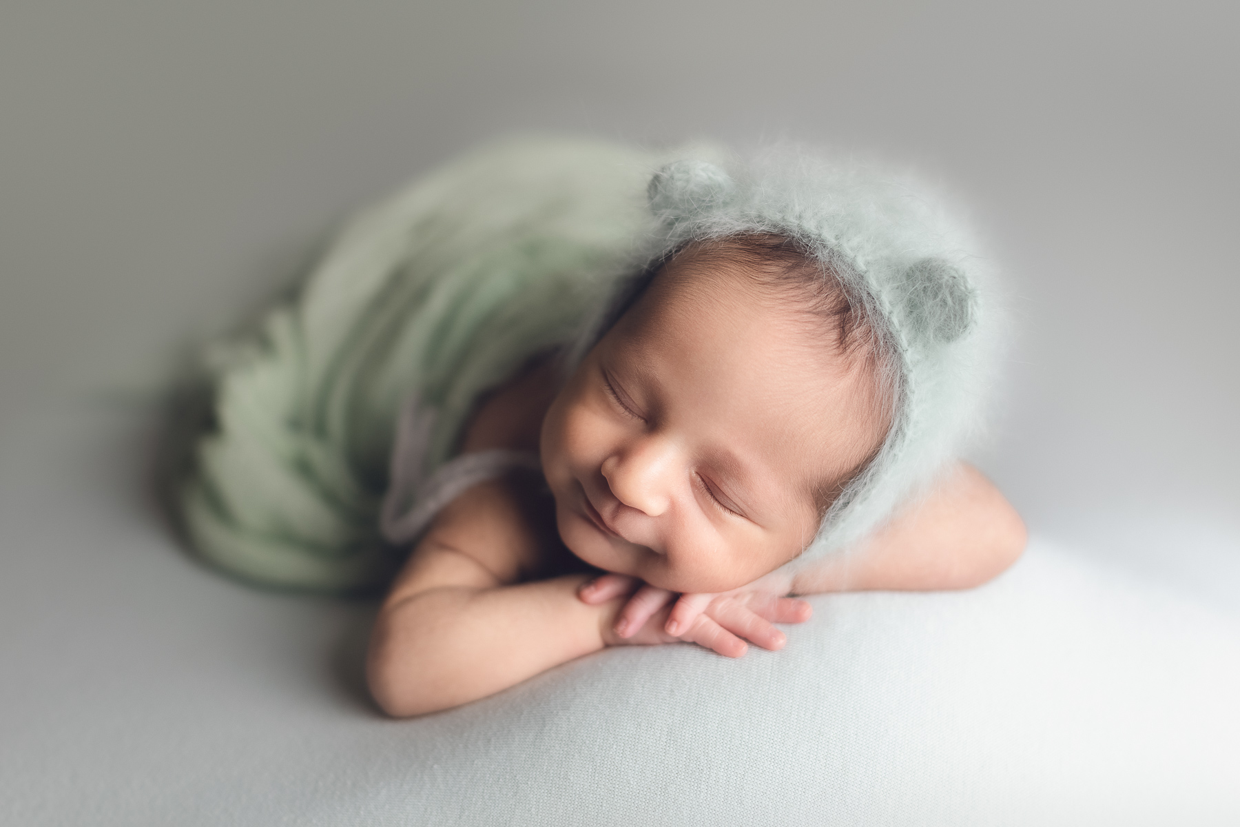 Newborn baby only photography package on sale - baby boy smiling on a green background and bear hat