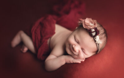 newborn photography classic package sample - baby girl smiling in a red background fabric