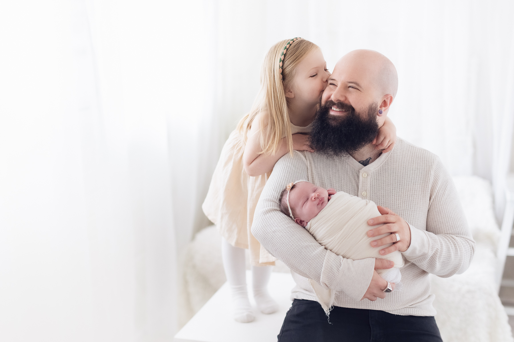 dad holding his newborn baby girl in a natural light studio. newborn photography burnaby