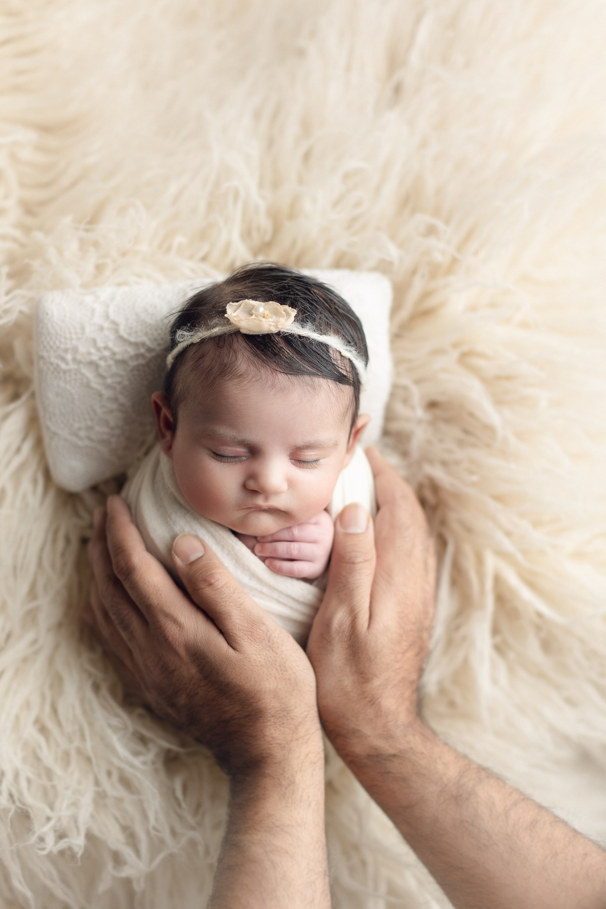 dad holding newborn in a white fur