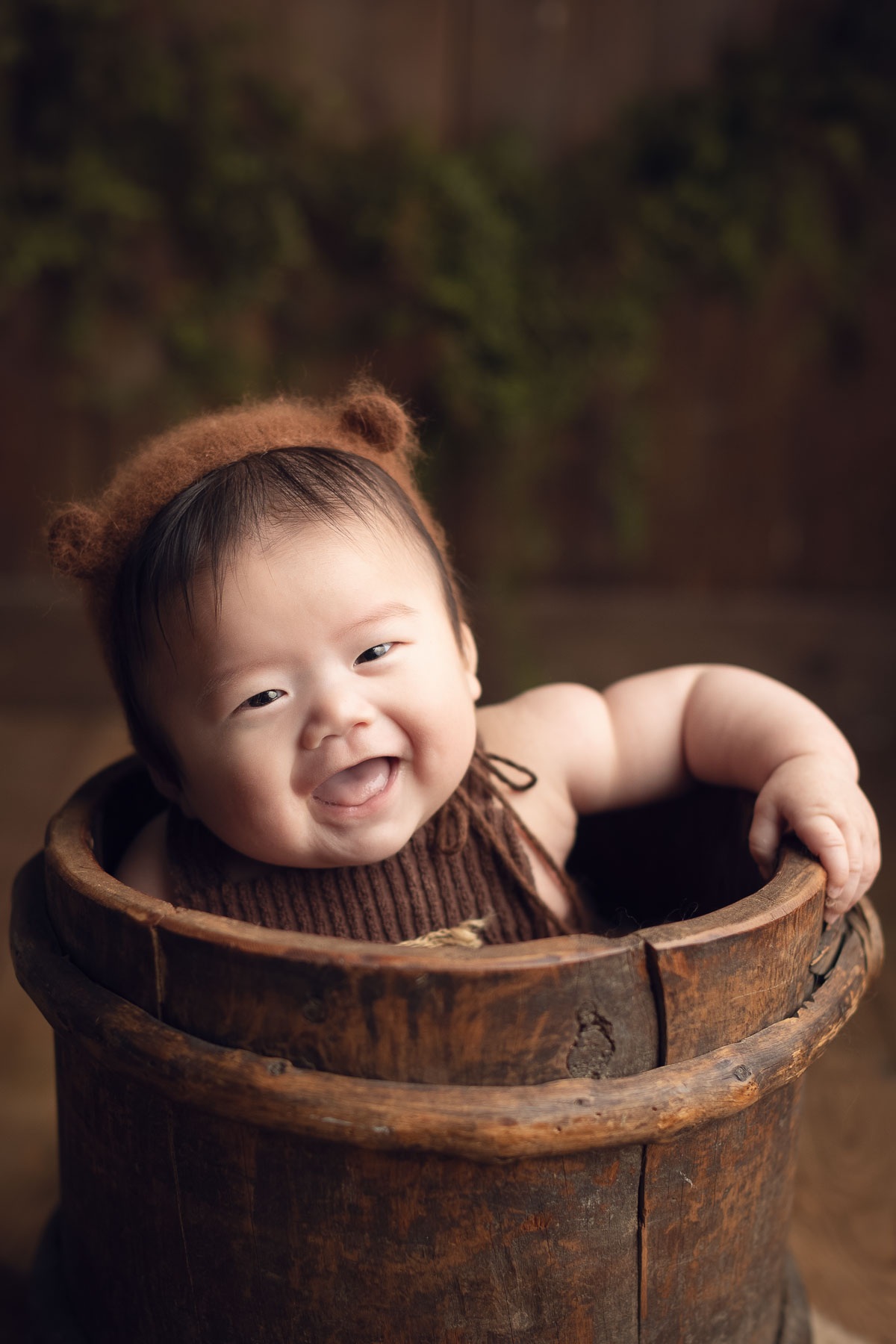 100 days old baby boy smiling in a brown bucket