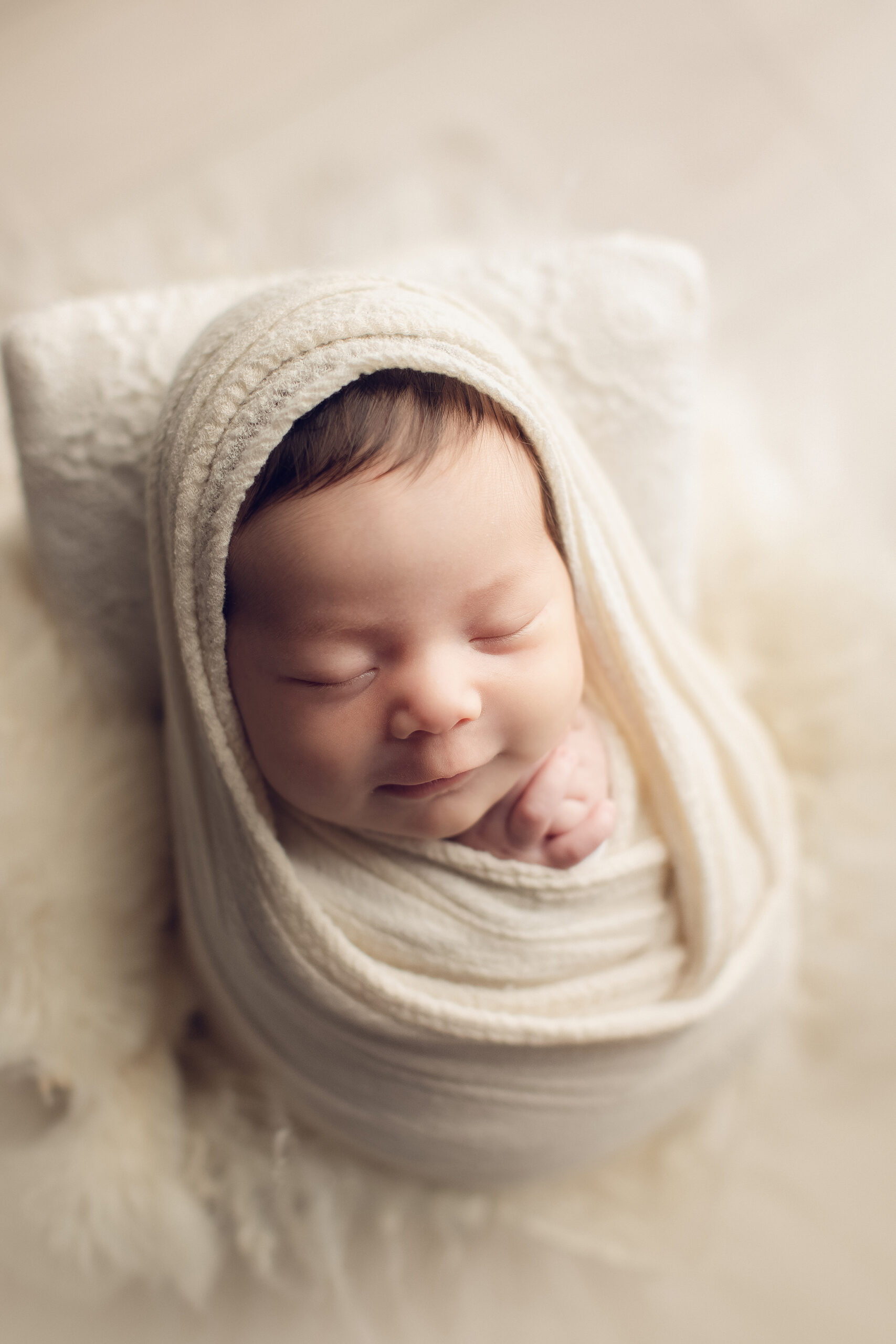 newborn baby girl wrapped in cream color 