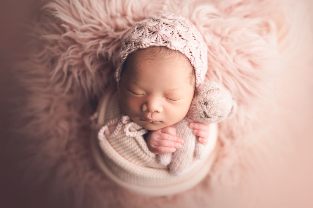 pink setup for newborn photography with teddy bear