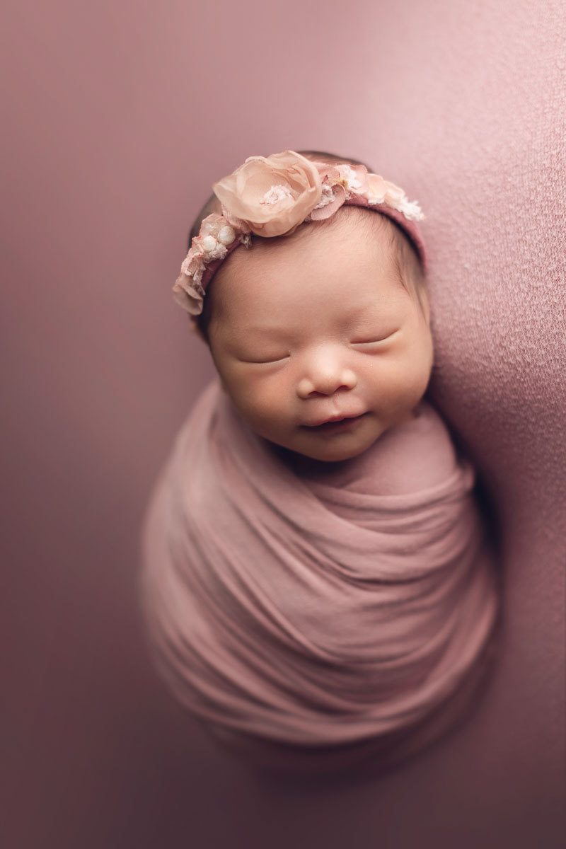 newborn baby girl smiling for photographer