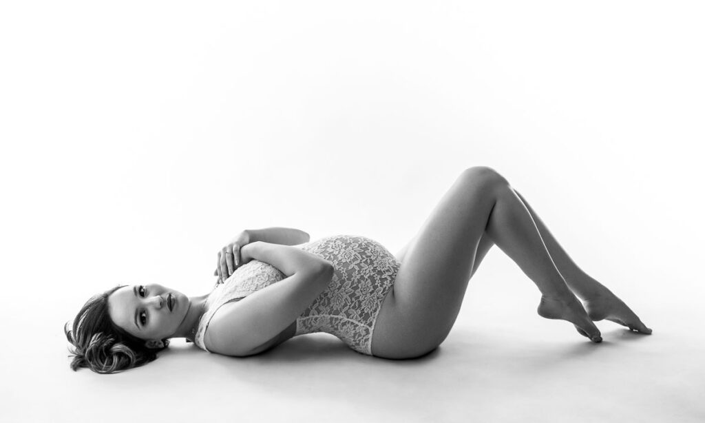 Boudoir-style maternity portrait in white lace lingerie