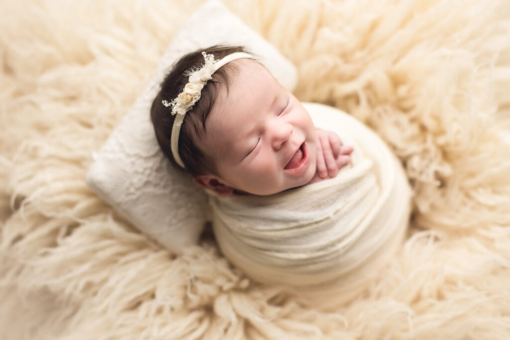 newborn baby smiling in a creamy background