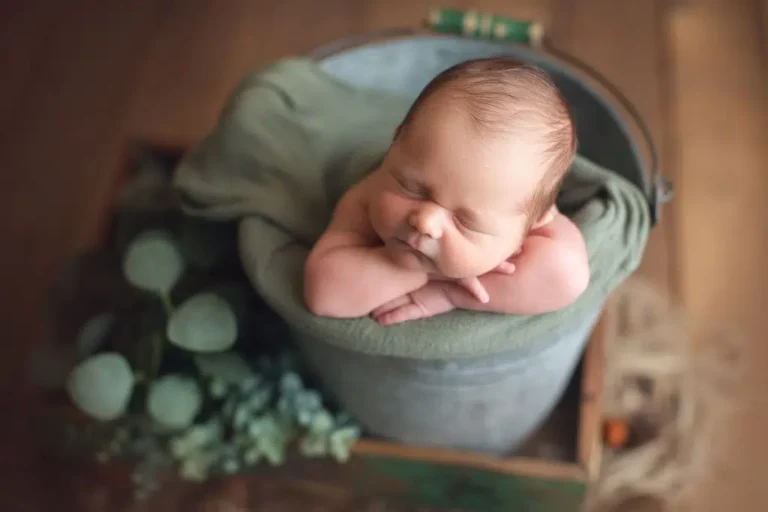 Newborn baby sleeping in soft beige wrap at Jana Photography studio in Surrey