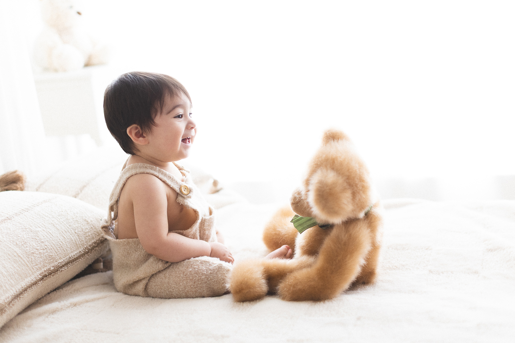 Baby smiling with teddy bear.
