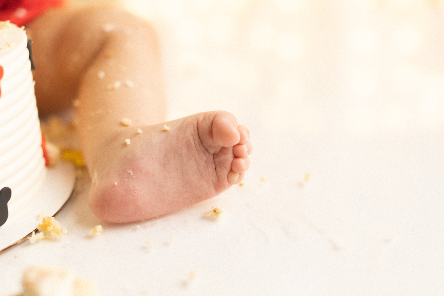 Baby's foot near cake remnants.