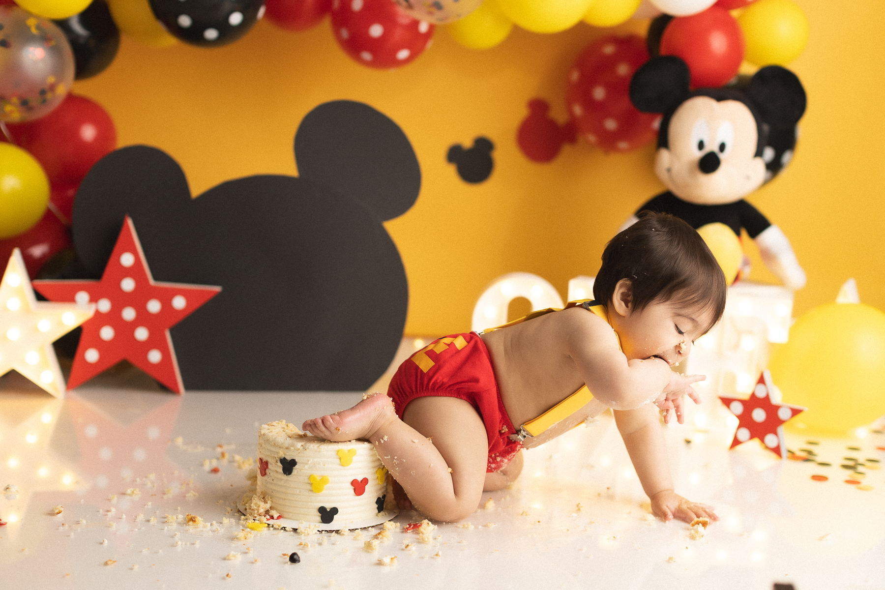 Baby enjoying Mickey Mouse cake smash