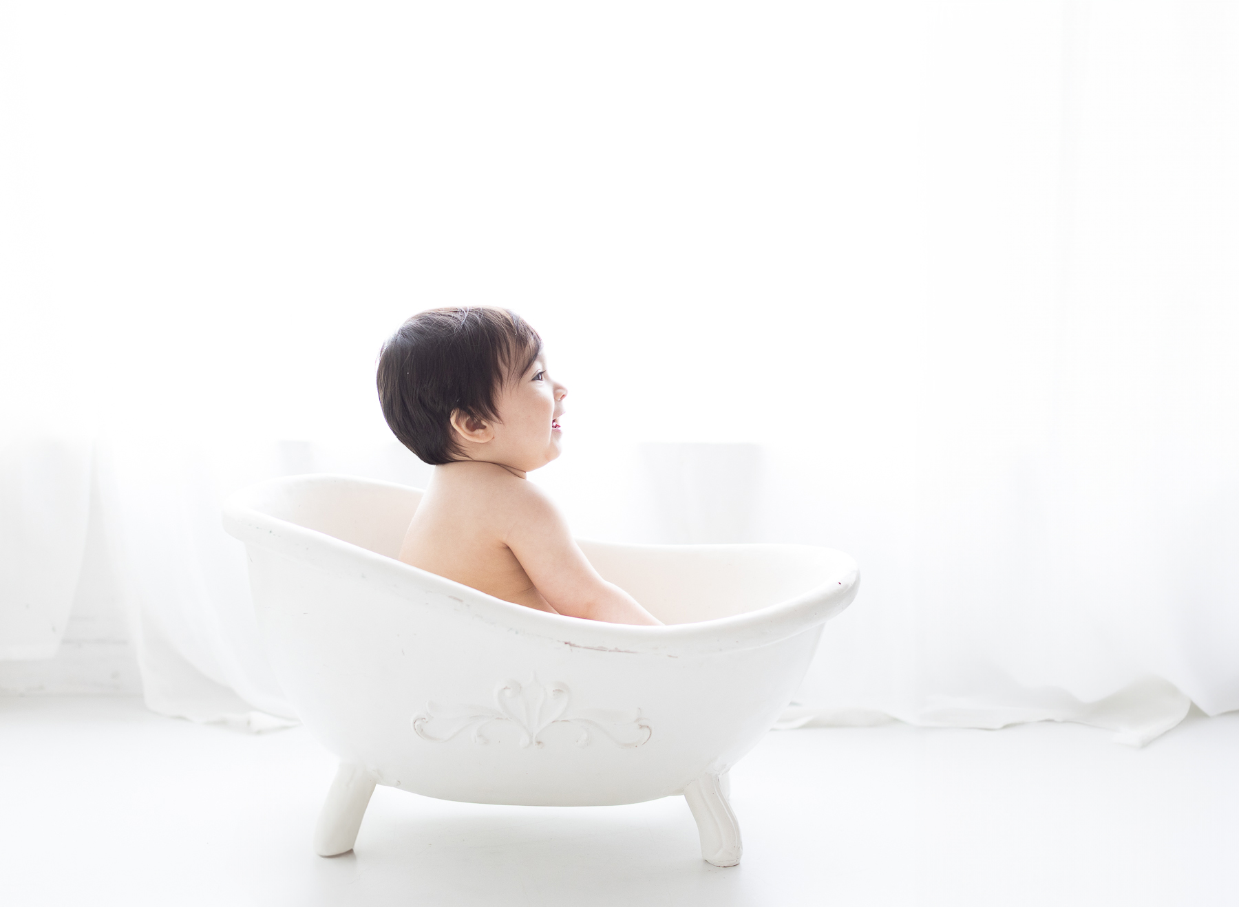 Baby in bathtub, bright natural light.