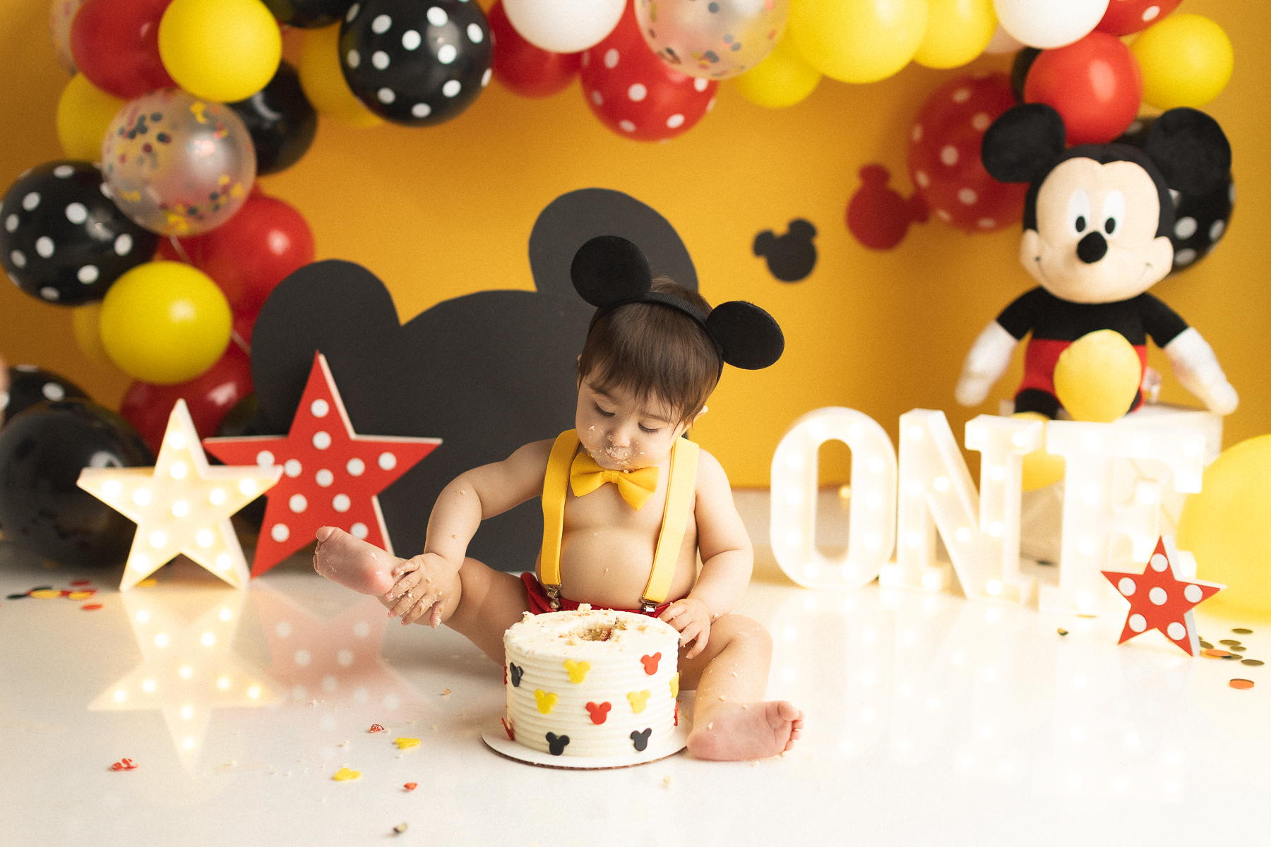 Child enjoying Mickey Mouse cake smash