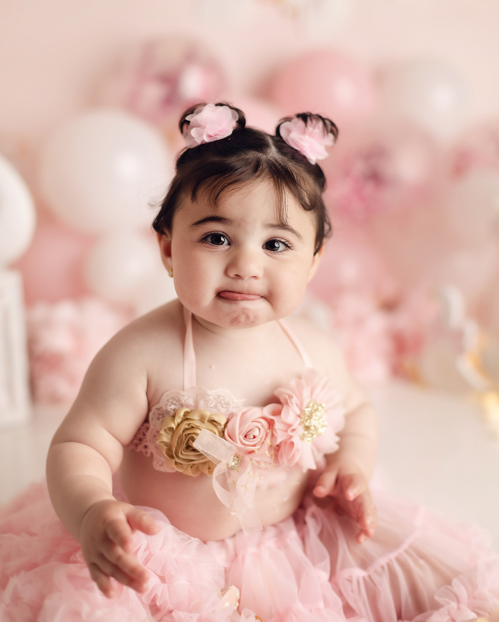 Baby girl enjoying pink swan cake smash photography session in Vancouver studio with pastel balloons and luxury birthday setup