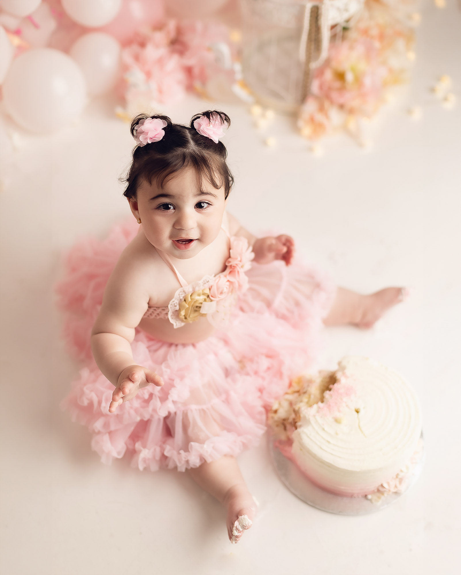 Close up of first birthday cake with baby feet during elegant pink cake smash session in Vancouver