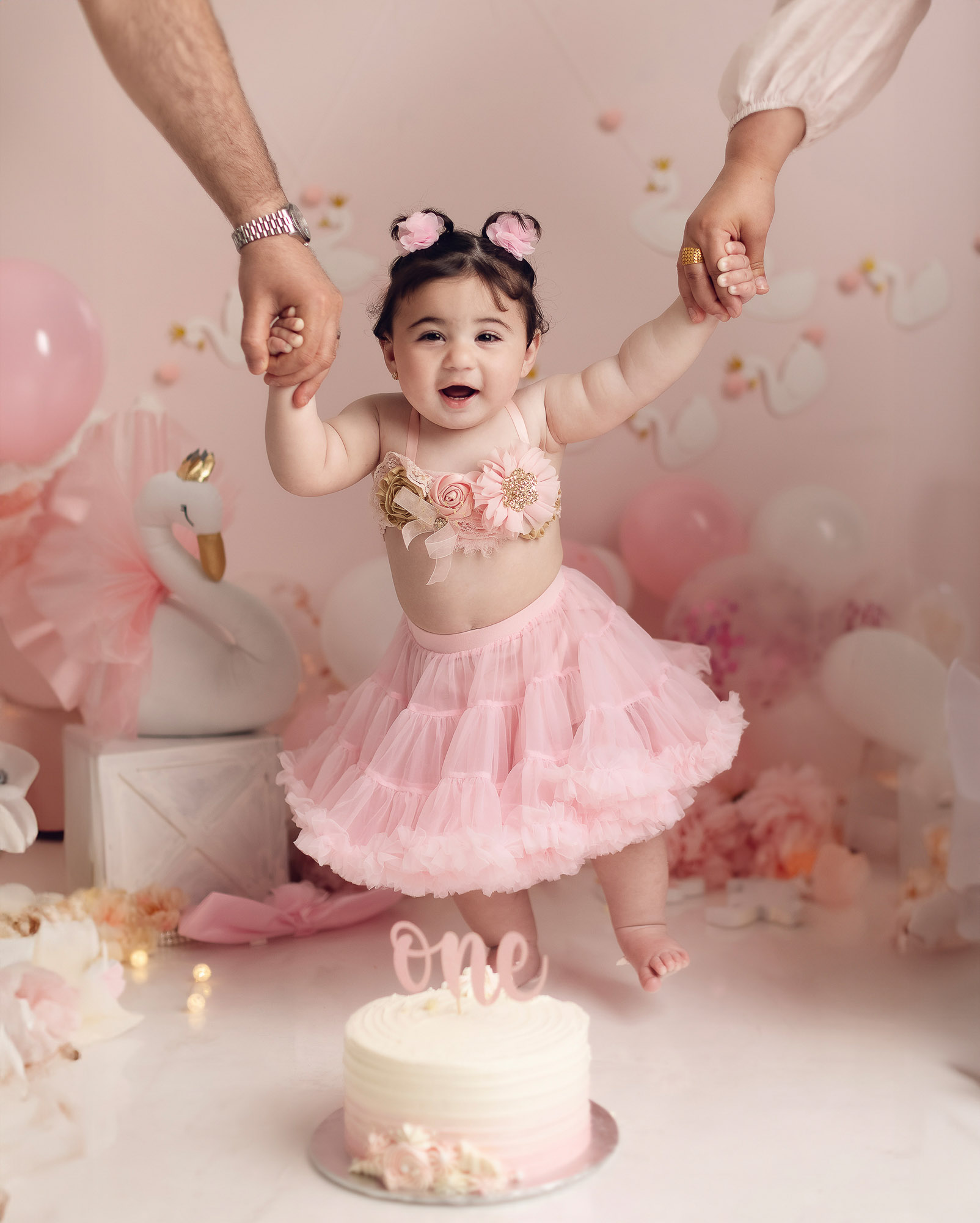 mom and dd holding baby girls hand in her birthday cake smash photography vancouver