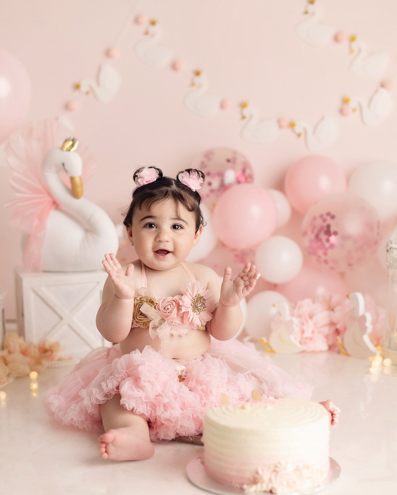 One year old baby girl sitting beside birthday cake during luxury cake smash photography session in Vancouver