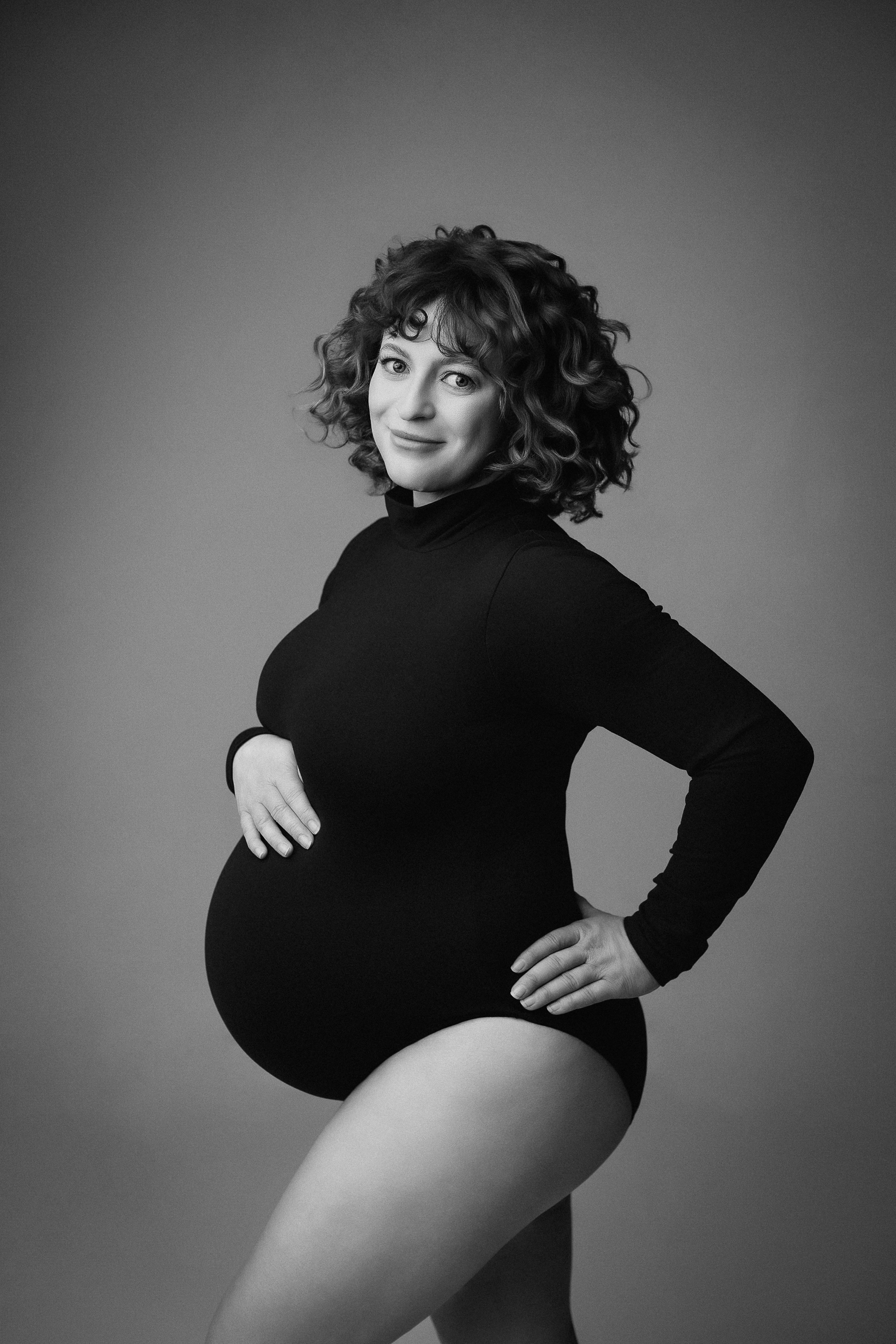 Elegant maternity bodysuit photoshoot in Vancouver studio with artistic lighting and soft posing in black and white