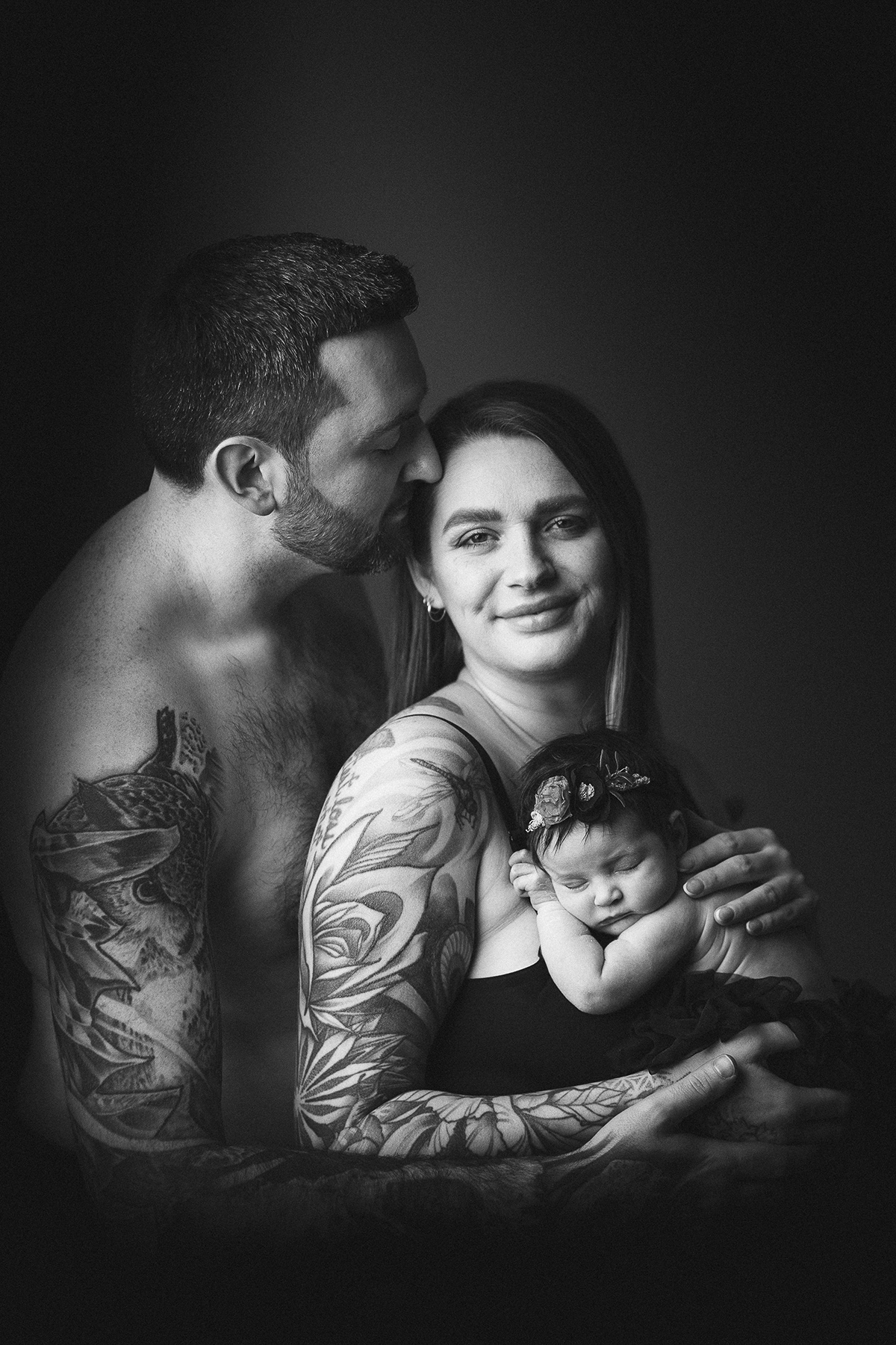 Parents embracing while holding their newborn baby, black and white family portrait Vancouver